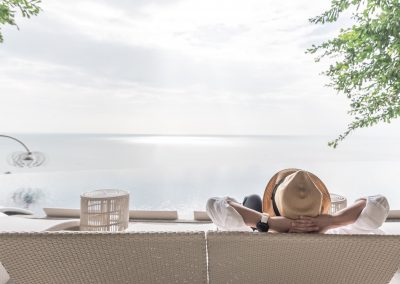 woman lounging on patio furniture looking out at water