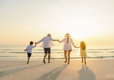 family holding hands on beach at sunset